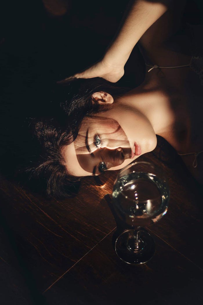 Mastering the First Impression: Your intriguing post title goes here Elegant portrait of a young woman lying beside a wine glass, creating a dreamy and artistic composition.