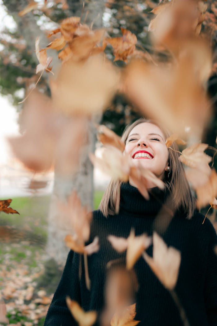 Crafting Captivating Headlines: Your awesome post title goes here Joyful woman in autumn setting surrounded by falling leaves, embracing the season's beauty.