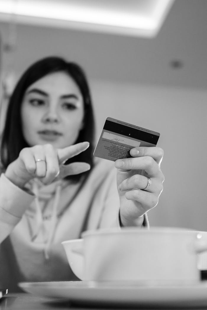 gallery-5 Black-and-white image of a woman pointing at a credit card indoors.
