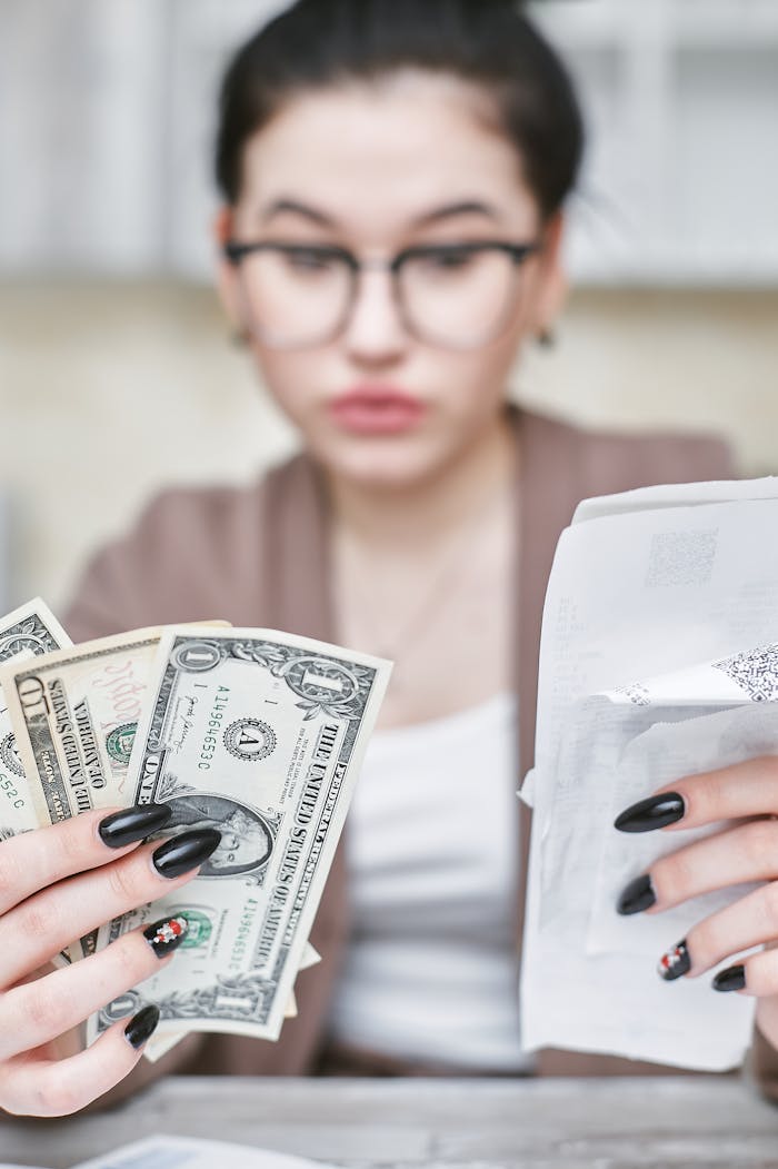 Focused young woman handling dollar bills and receipts, highlighting financial management skills.